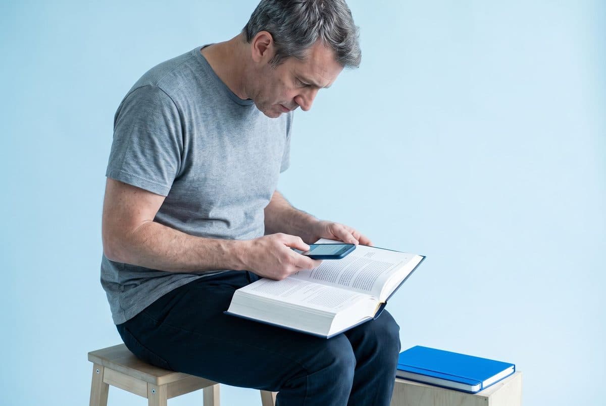 Man in his late forties scanning a textbook page with his phone.